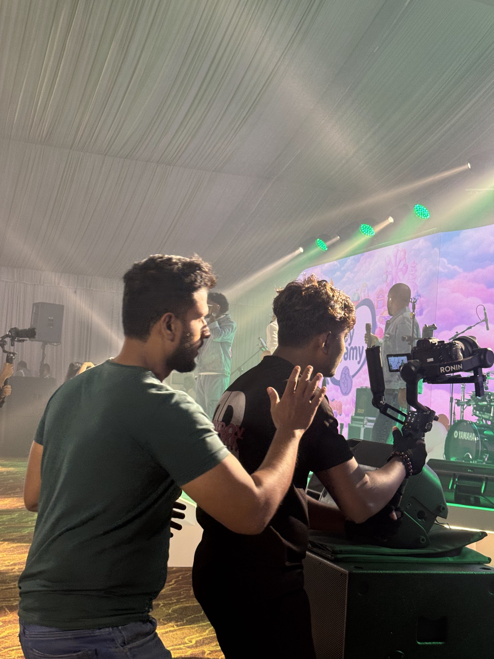 Two crew members operating a camera gimbal beside an LED stage screen