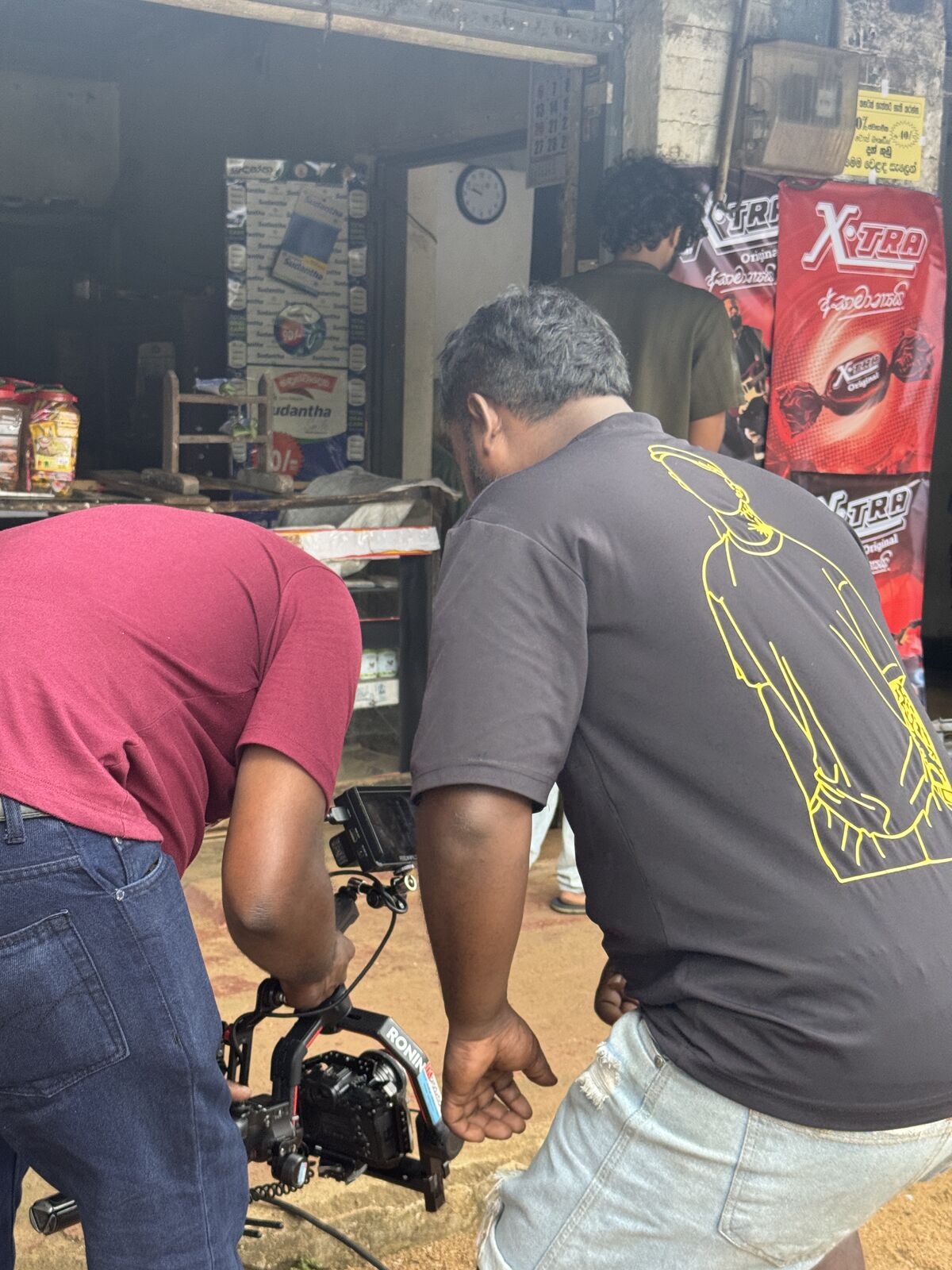 Camera assistant operating a gimbal-mounted camera on a teledrama location shoot at a roadside shop